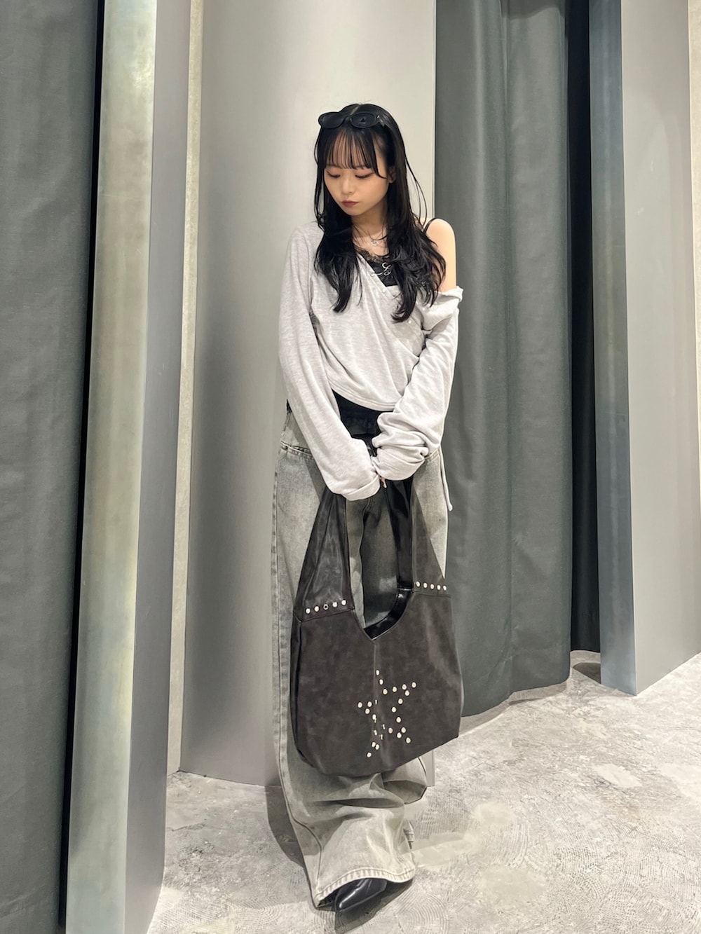 グレー系のトップス、ブラック系のキャミソール、グレー系のデニムパンツを着用したレディースの春コーディネートの2枚目の写真