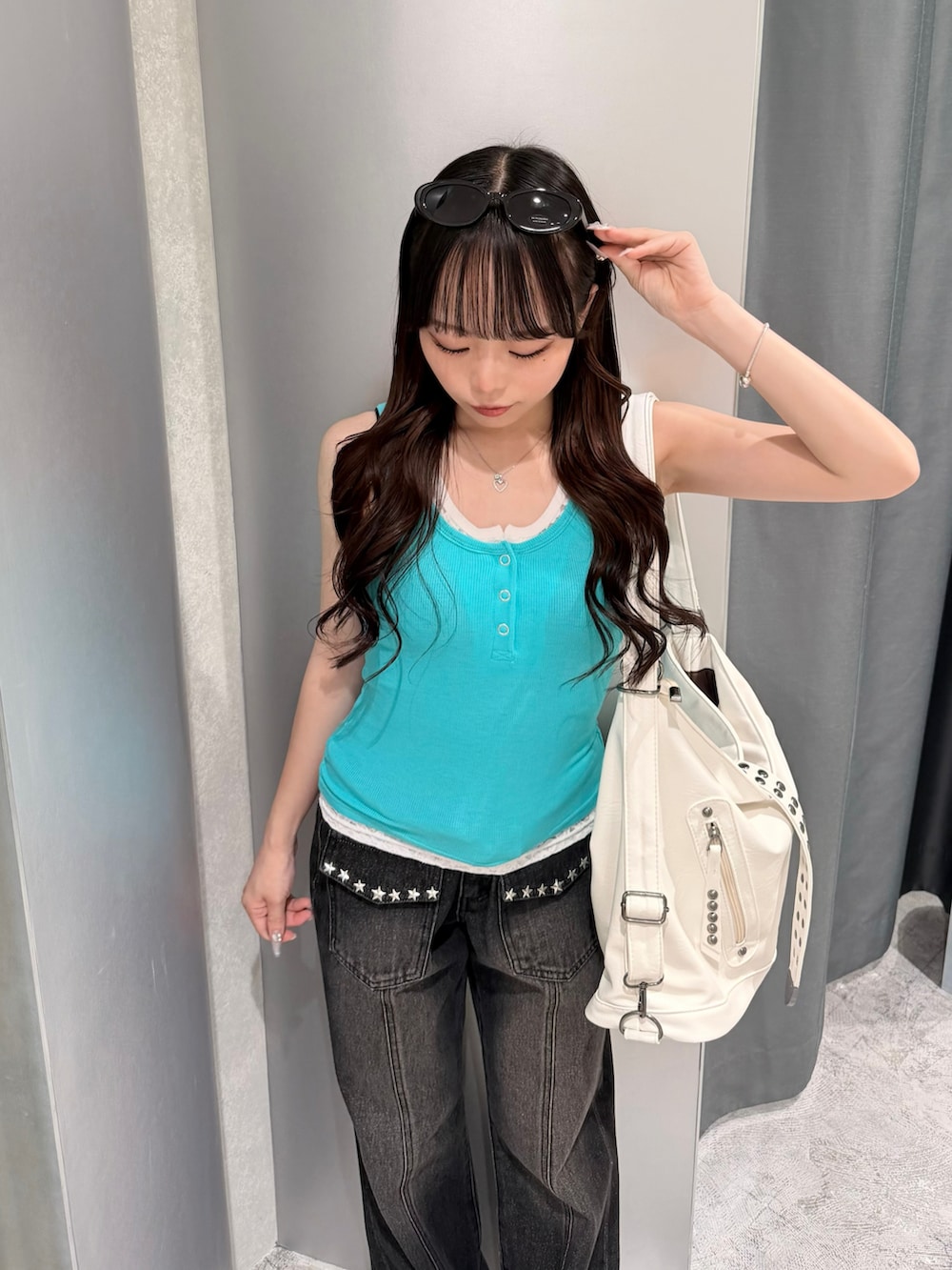 グリーン系のタンクトップ、ブラック系のデニムパンツ、ホワイト系のパンプスを着用したレディースの夏コーディネートの4枚目の写真