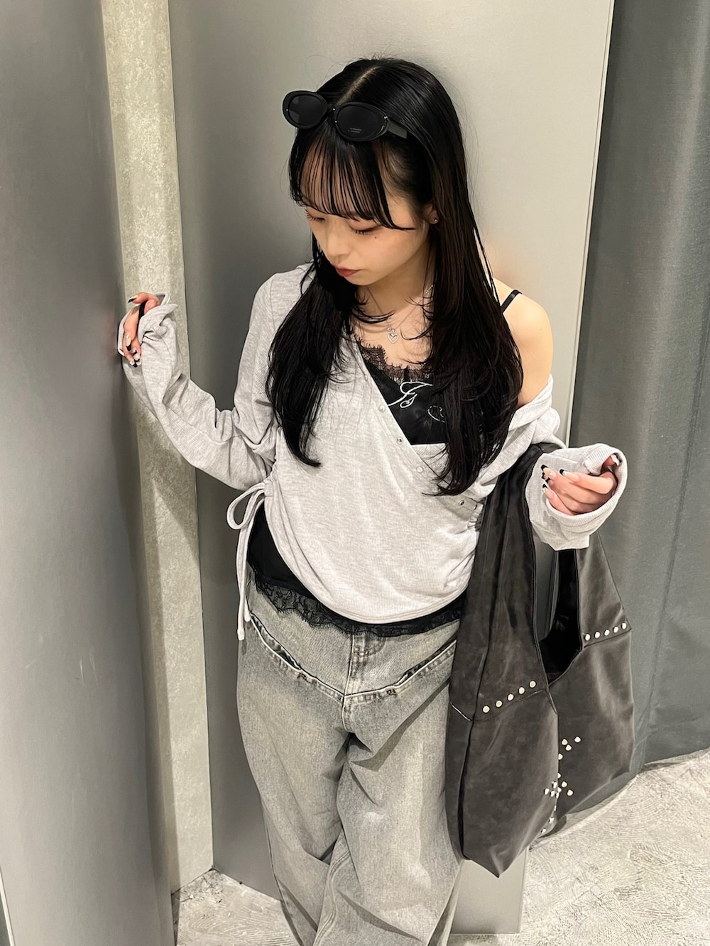 グレー系のトップス、ブラック系のキャミソール、グレー系のデニムパンツを着用したレディースの春コーディネートの4枚目の写真