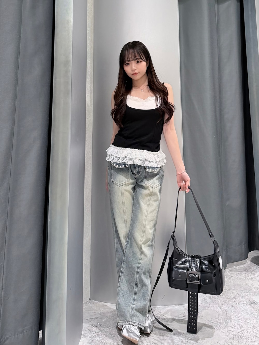 ブラック系のタンクトップ、ブルー系のデニムパンツ、ホワイト系のスニーカーを着用したレディースの夏コーディネートの2枚目の写真