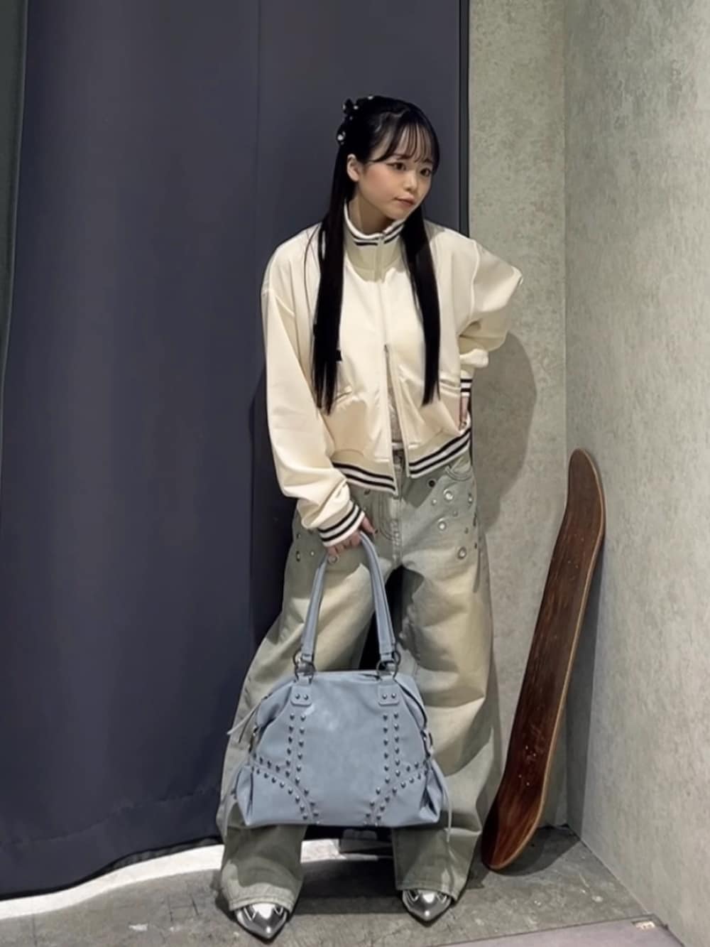 ホワイト系のブルゾン、ホワイト系のキャミソール、ブルー系のショルダーバッグを着用したレディースの冬コーディネートの3枚目の写真