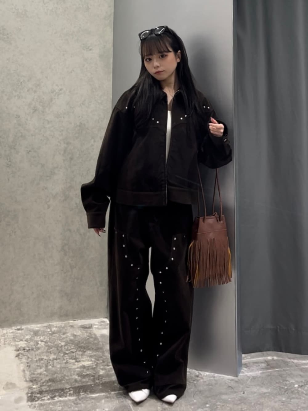 ブラウン系のショルダーバッグ、ホワイト系のキャミソール、ブラウン系のブルゾンを着用したレディースの秋コーディネートの3枚目の写真