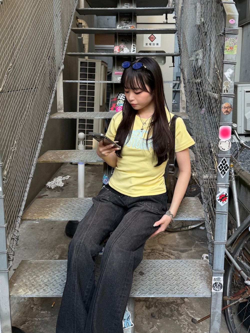 イエロー系のTシャツ/カットソー、ブラック系のデニムパンツ、ブラック系のサンダルを着用したレディースの春コーディネートの3枚目の写真