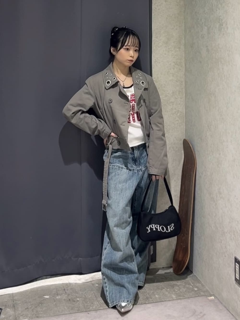 ブラック系のショルダーバッグ、グレー系のピーコート、ブルー系のデニムパンツを着用したレディースの春コーディネートの2枚目の写真