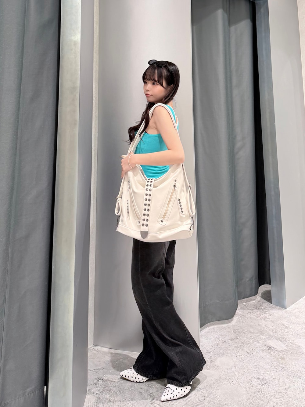 グリーン系のタンクトップ、ブラック系のデニムパンツ、ホワイト系のパンプスを着用したレディースの夏コーディネートの3枚目の写真