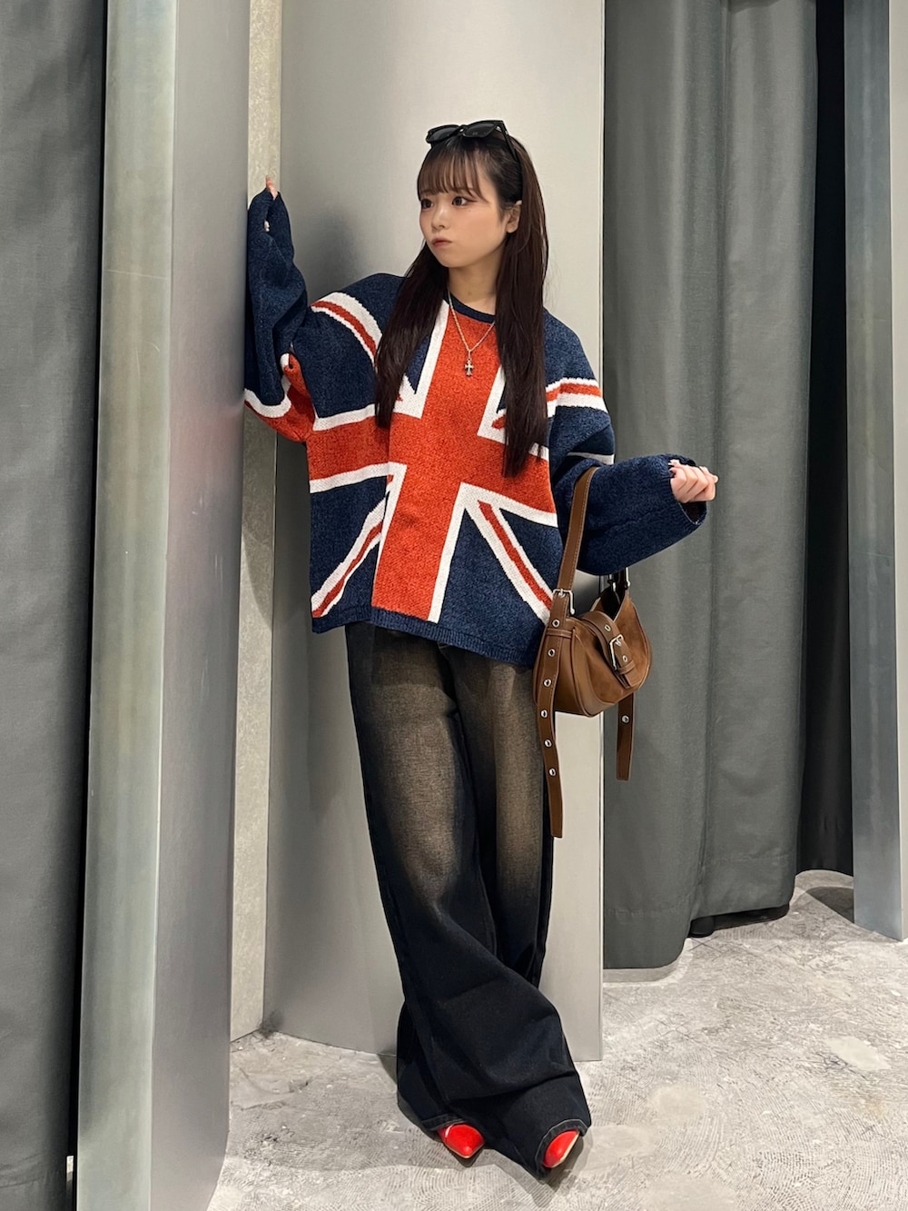 ブルー系のニット/セーター、ブルー系のデニムパンツ、ブラウン系のショルダーバッグを着用したレディースの秋コーディネートの2枚目の写真