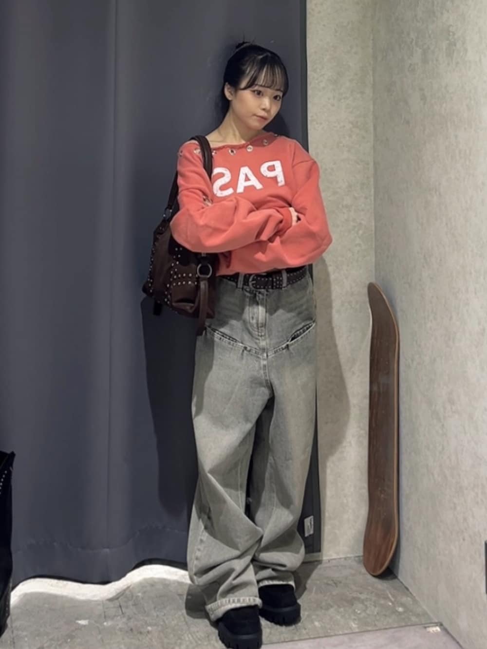 オレンジ系のスウェット、グレー系のデニムパンツ、ブラウン系のショルダーバッグを着用したレディースの冬コーディネートの2枚目の写真