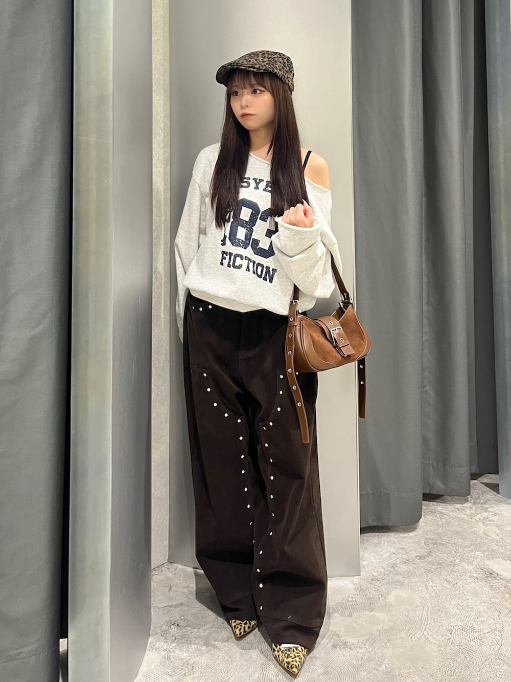 グレー系のスウェット、ブラウン系のショルダーバッグ、ブラウン系のパンツを着用したレディースの秋コーディネートの2枚目の写真