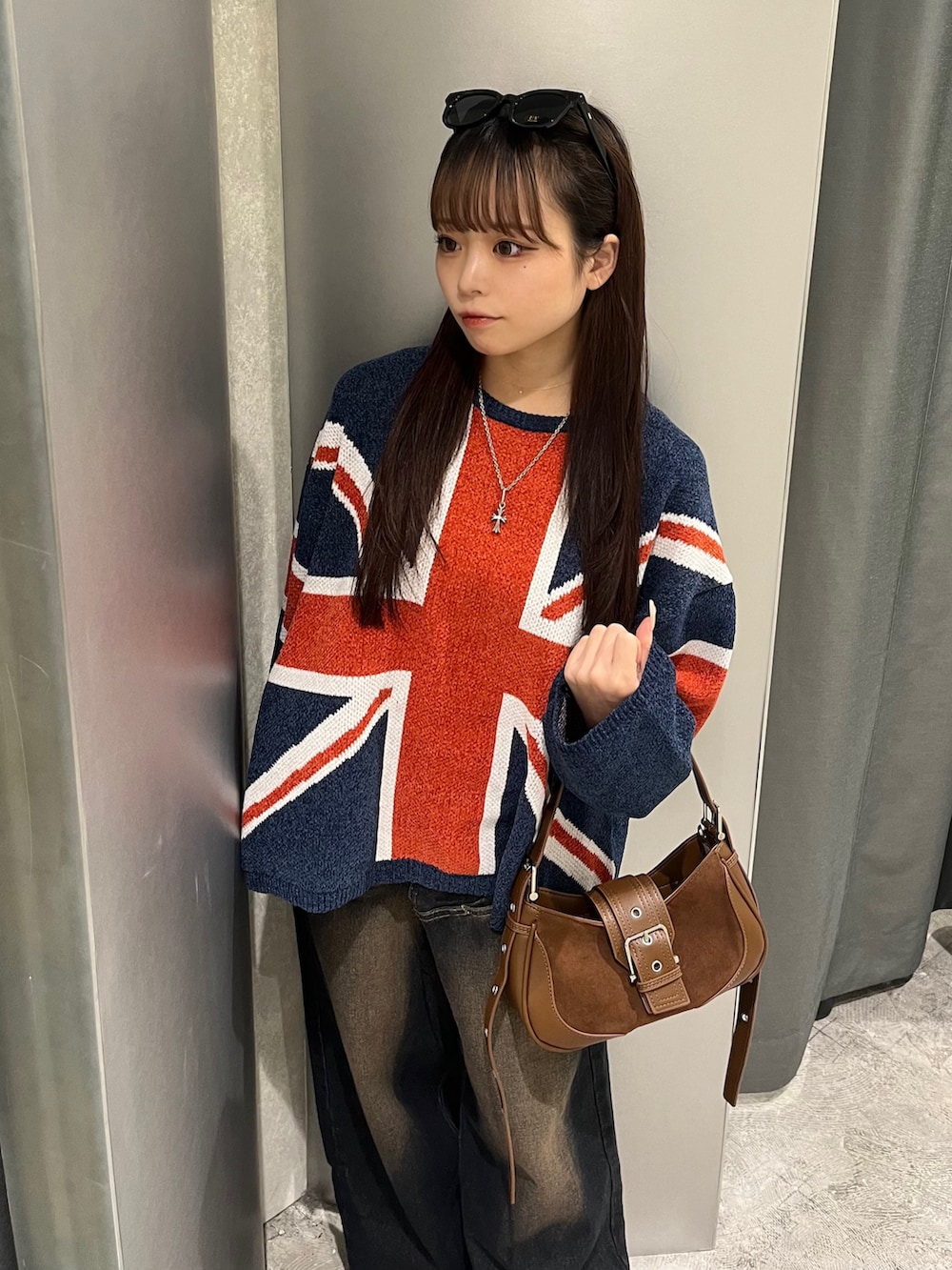 ブルー系のニット/セーター、ブルー系のデニムパンツ、ブラウン系のショルダーバッグを着用したレディースの秋コーディネートの3枚目の写真