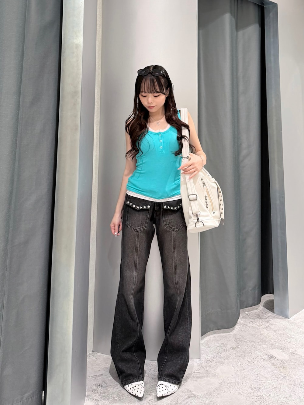 グリーン系のタンクトップ、ブラック系のデニムパンツ、ホワイト系のパンプスを着用したレディースの夏コーディネートの2枚目の写真