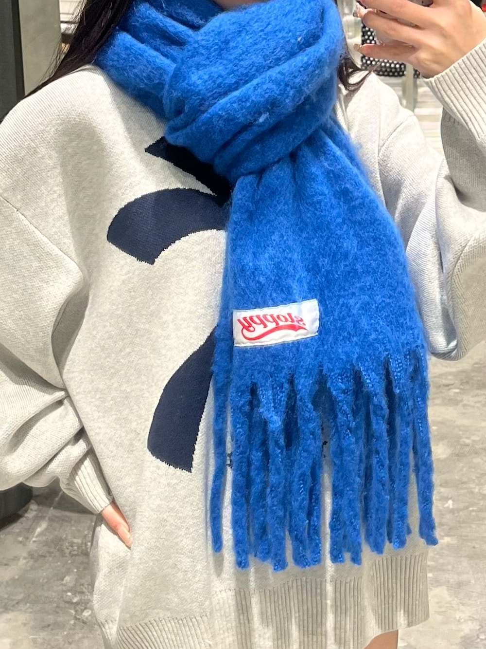 ホワイト系のニット/セーター、グレー系のその他パンツ、ブルー系のマフラーを着用したレディースの秋コーディネートの2枚目の写真