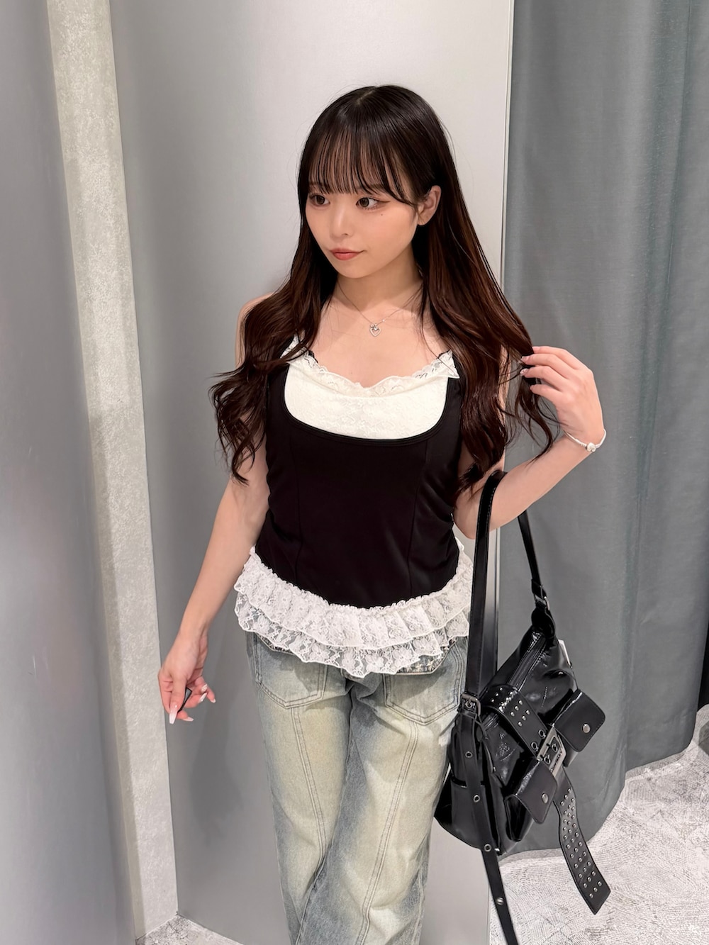 ブラック系のタンクトップ、ブルー系のデニムパンツ、ホワイト系のスニーカーを着用したレディースの夏コーディネートの4枚目の写真