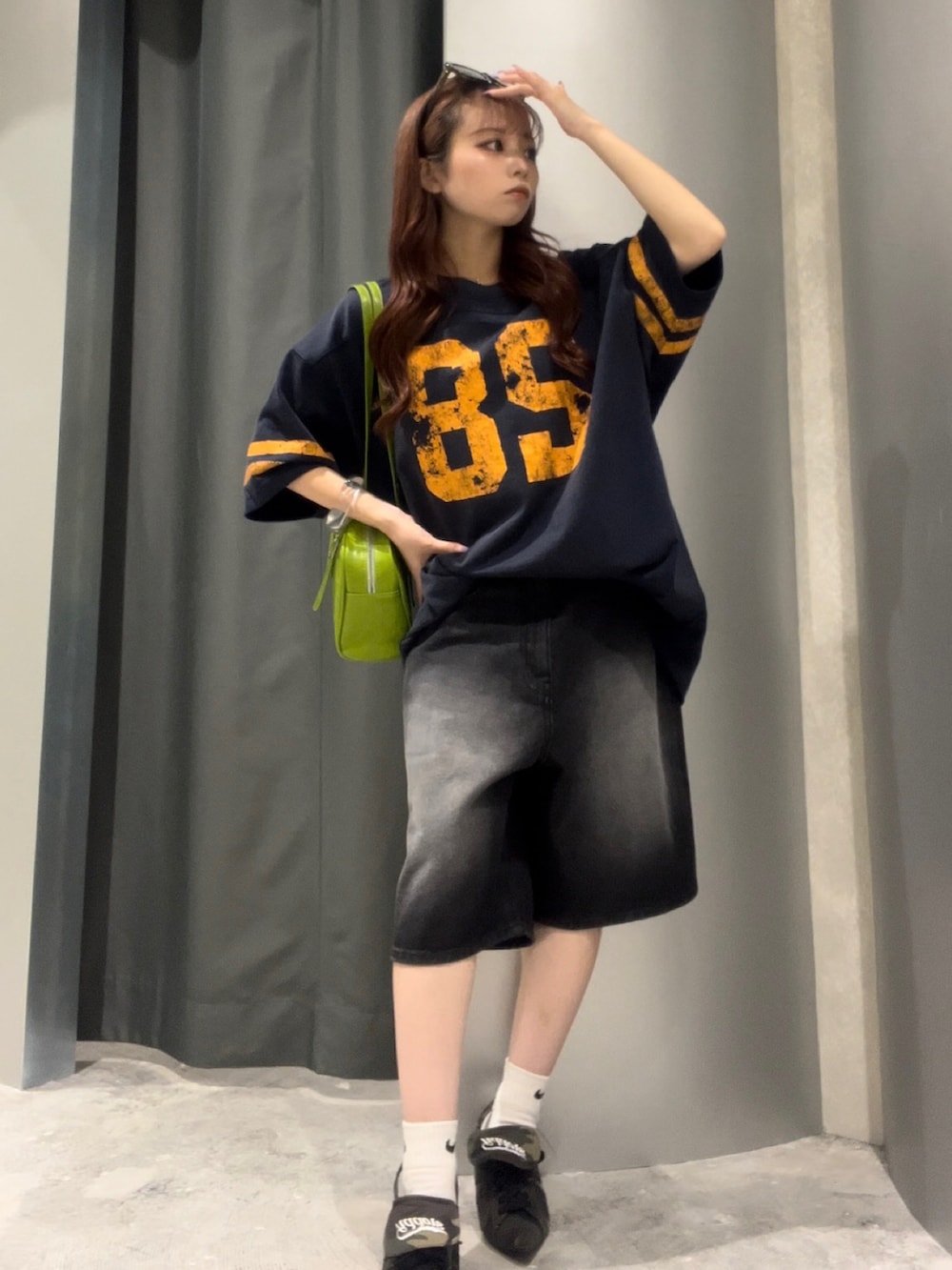ブラック系のデニムパンツ、グリーン系のショルダーバッグ、ブルー系のTシャツ/カットソーを着用したレディースの夏コーディネートの2枚目の写真