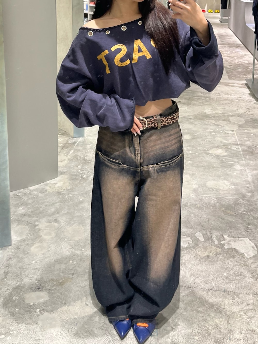 ブルー系のスウェット、ブルー系のデニムパンツ、ブラウン系のショルダーバッグを着用したレディースの秋コーディネートの2枚目の写真