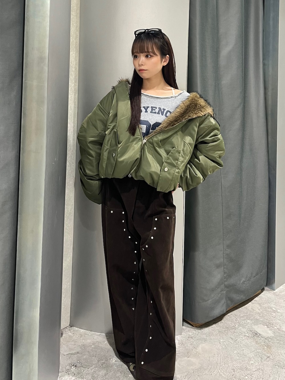 グリーン系のブルゾン、グレー系のスウェット、ブラウン系のパンツを着用したレディースの秋コーディネートの2枚目の写真