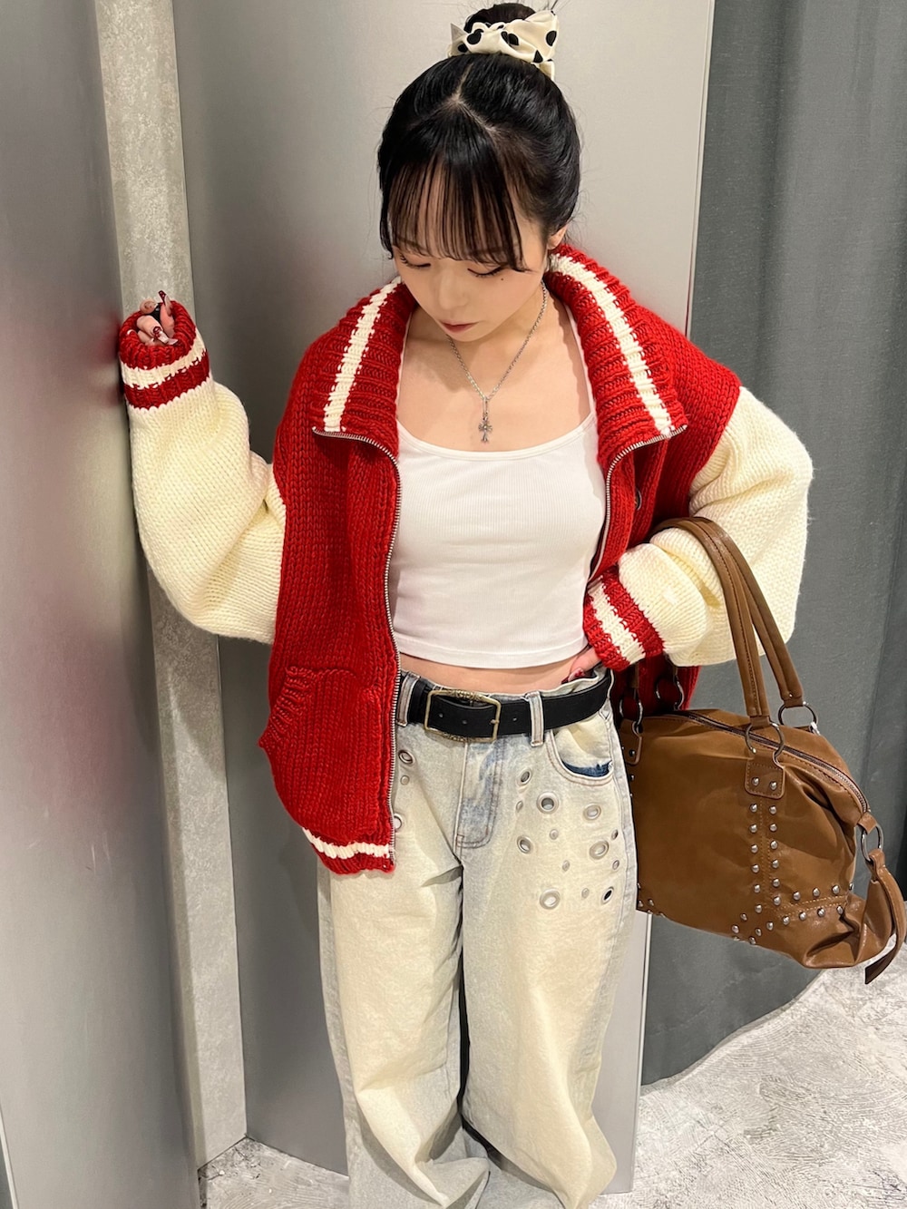 レッド系のスタジャン、ブルー系のデニムパンツ、ブラウン系のショルダーバッグを着用したレディースの冬コーディネートの2枚目の写真