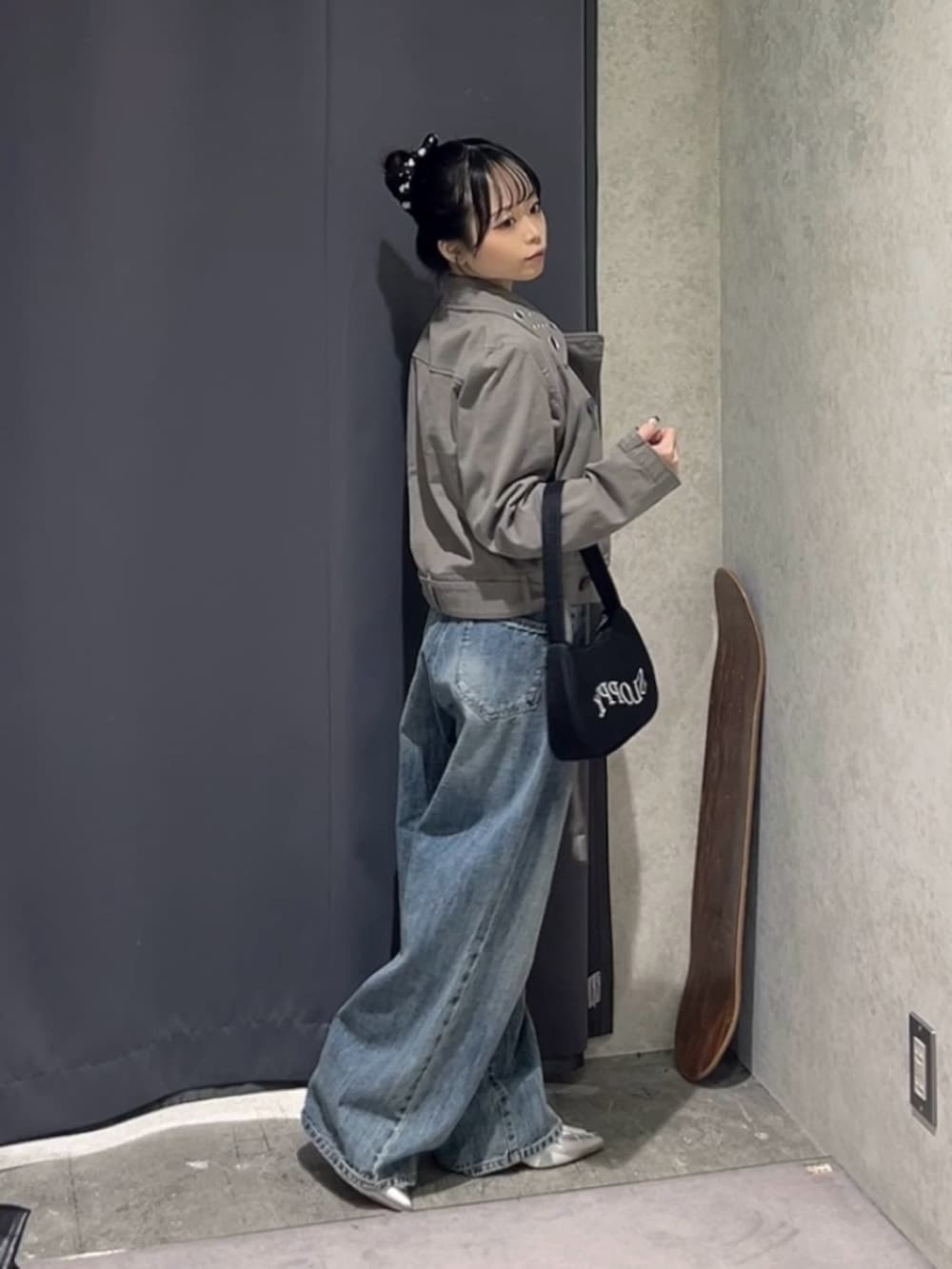 ブラック系のショルダーバッグ、グレー系のピーコート、ブルー系のデニムパンツを着用したレディースの春コーディネートの3枚目の写真