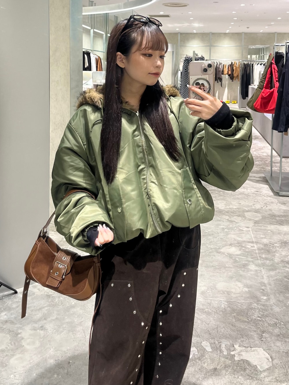 グリーン系のブルゾン、ブラウン系のパンツ、ブラウン系のショルダーバッグを着用したレディースの秋コーディネートの3枚目の写真