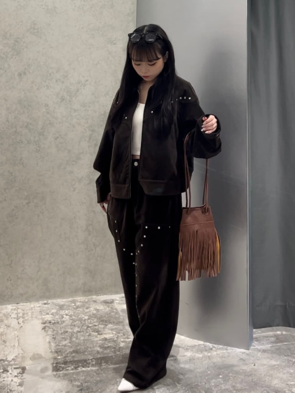 ブラウン系のショルダーバッグ、ホワイト系のキャミソール、ブラウン系のブルゾンを着用したレディースの秋コーディネートの2枚目の写真