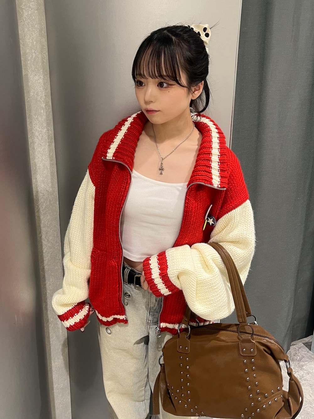 レッド系のスタジャン、ブルー系のデニムパンツ、ブラウン系のショルダーバッグを着用したレディースの冬コーディネートの3枚目の写真