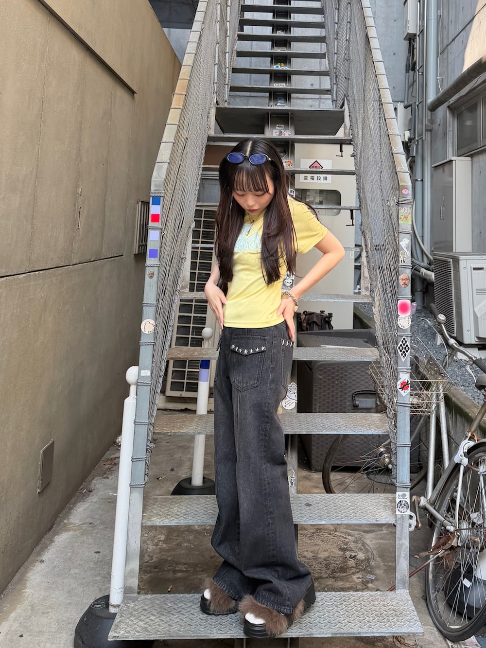 イエロー系のTシャツ/カットソー、ブラック系のデニムパンツ、ブラック系のサンダルを着用したレディースの春コーディネートの4枚目の写真