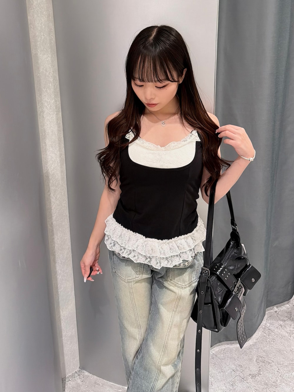 ブラック系のタンクトップ、ブルー系のデニムパンツ、ホワイト系のスニーカーを着用したレディースの夏コーディネートの3枚目の写真