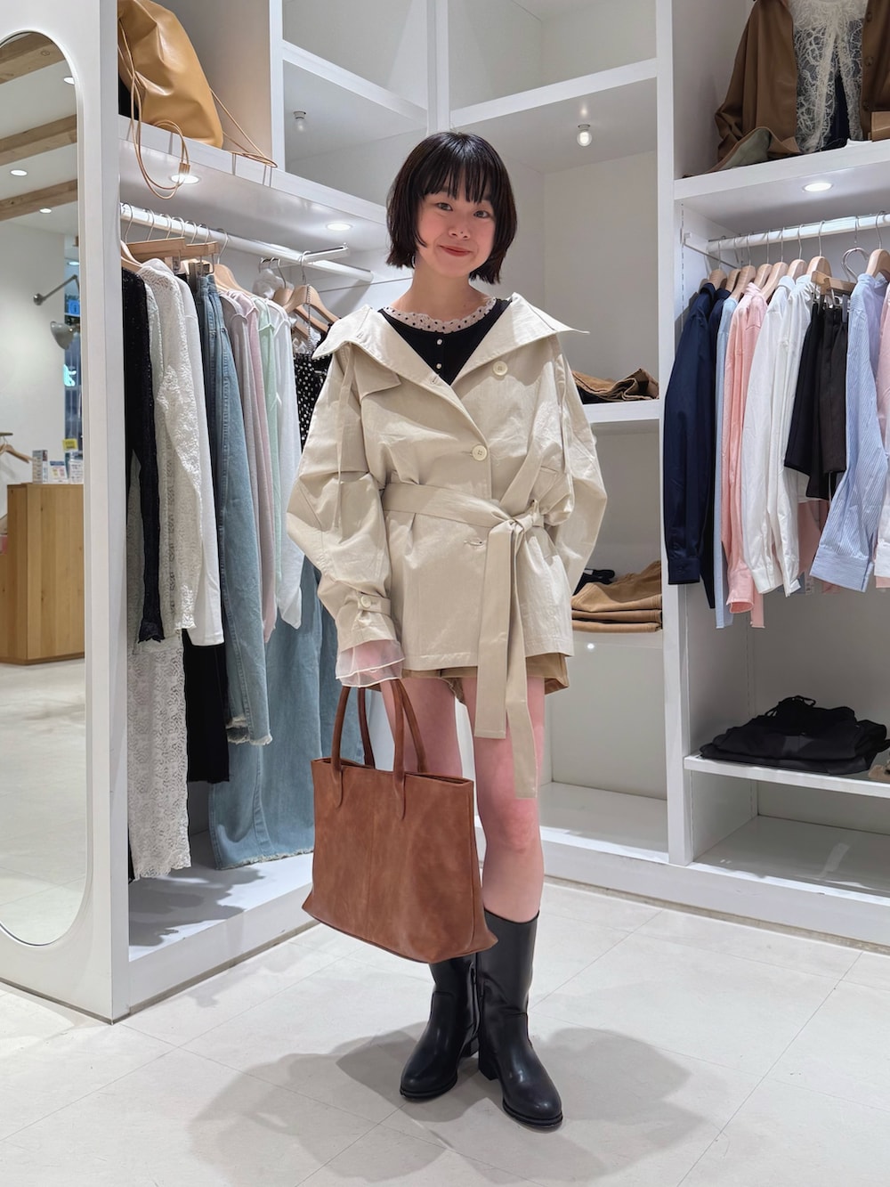 ホワイト系のトレンチコート、ホワイト系のTシャツ/カットソー、ブラック系のカーディガン/ボレロを着用したレディースの春コーディネートの2枚目の写真