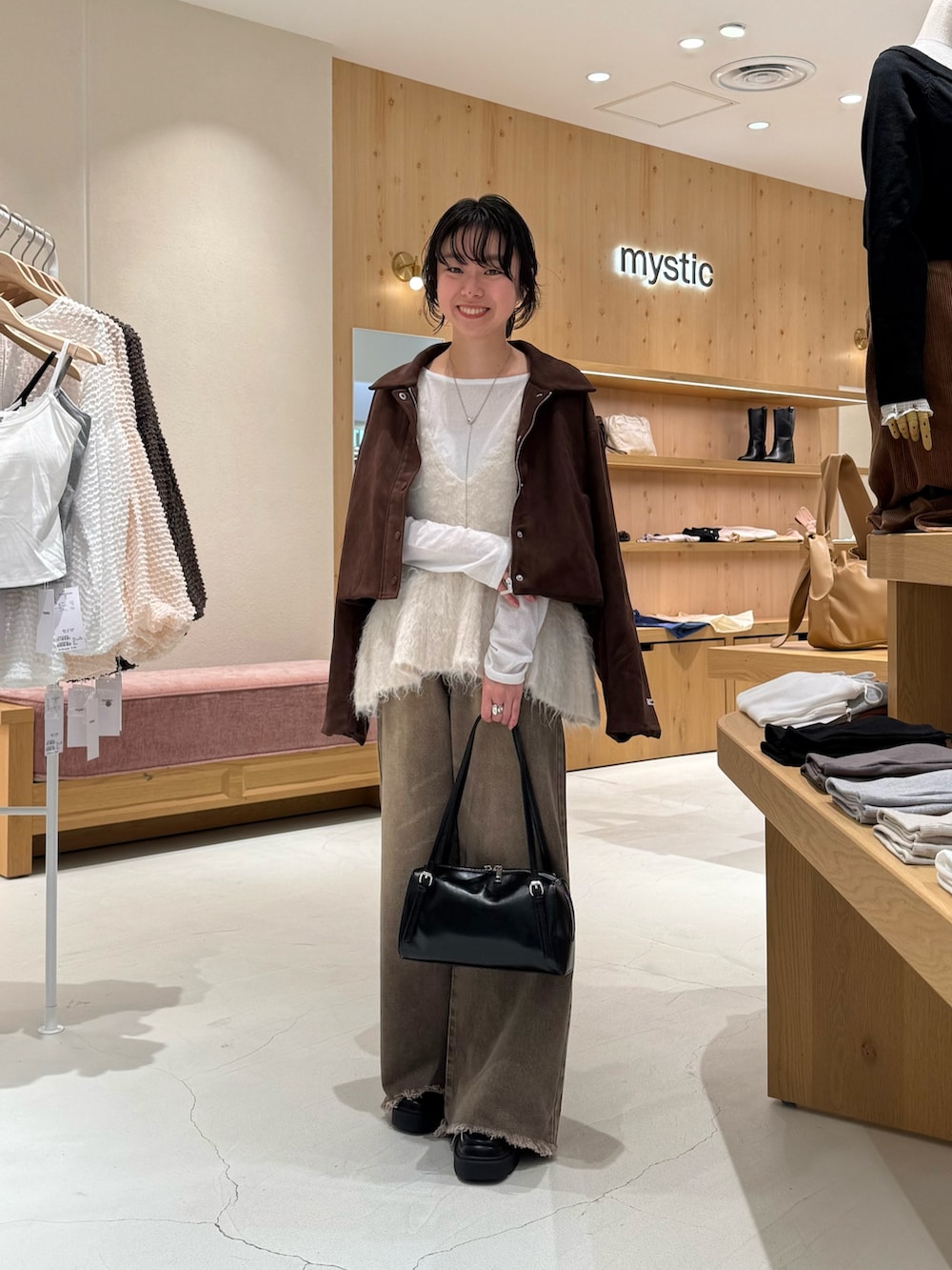 ブラウン系のブルゾン、ホワイト系のベスト、ホワイト系のTシャツ/カットソーを着用したレディースの秋コーディネートの2枚目の写真