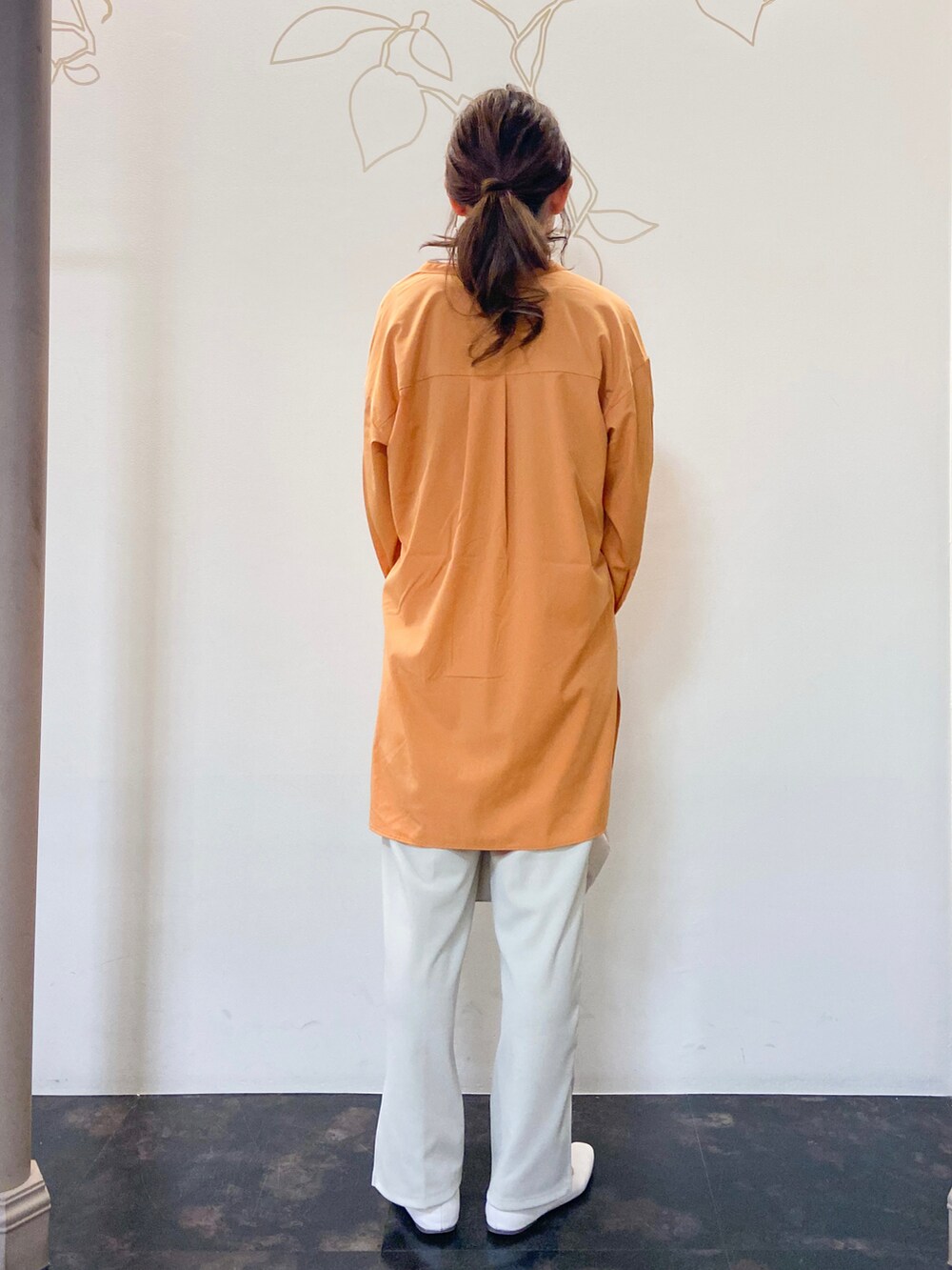 オレンジ系のシャツ/ブラウス、ブルー系のTシャツ/カットソー、ホワイト系のスラックスを着用したレディースの春コーディネートの4枚目の写真