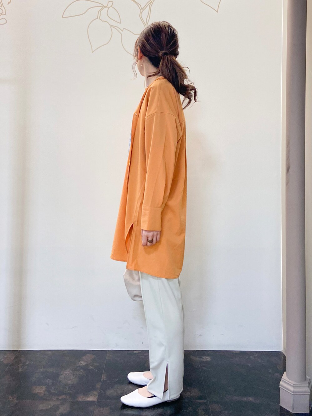 オレンジ系のシャツ/ブラウス、ブルー系のTシャツ/カットソー、ホワイト系のスラックスを着用したレディースの春コーディネートの3枚目の写真