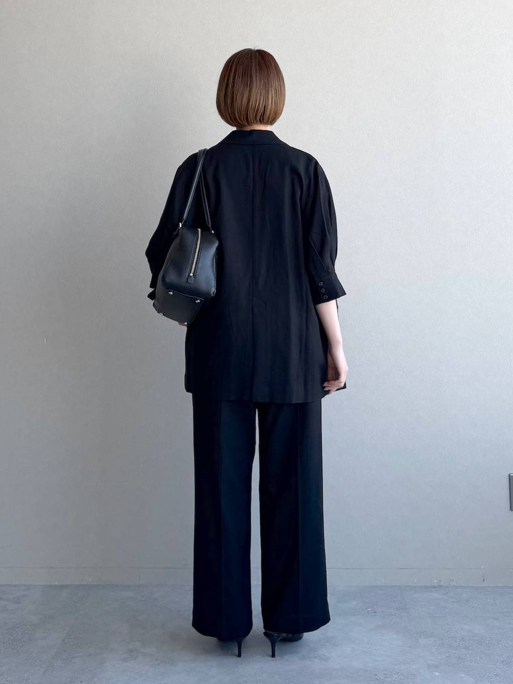 ブラック系のハンドバッグ、ブラック系のサンダル、ブラウン系のキャミソールを着用したレディースの春コーディネートの3枚目の写真