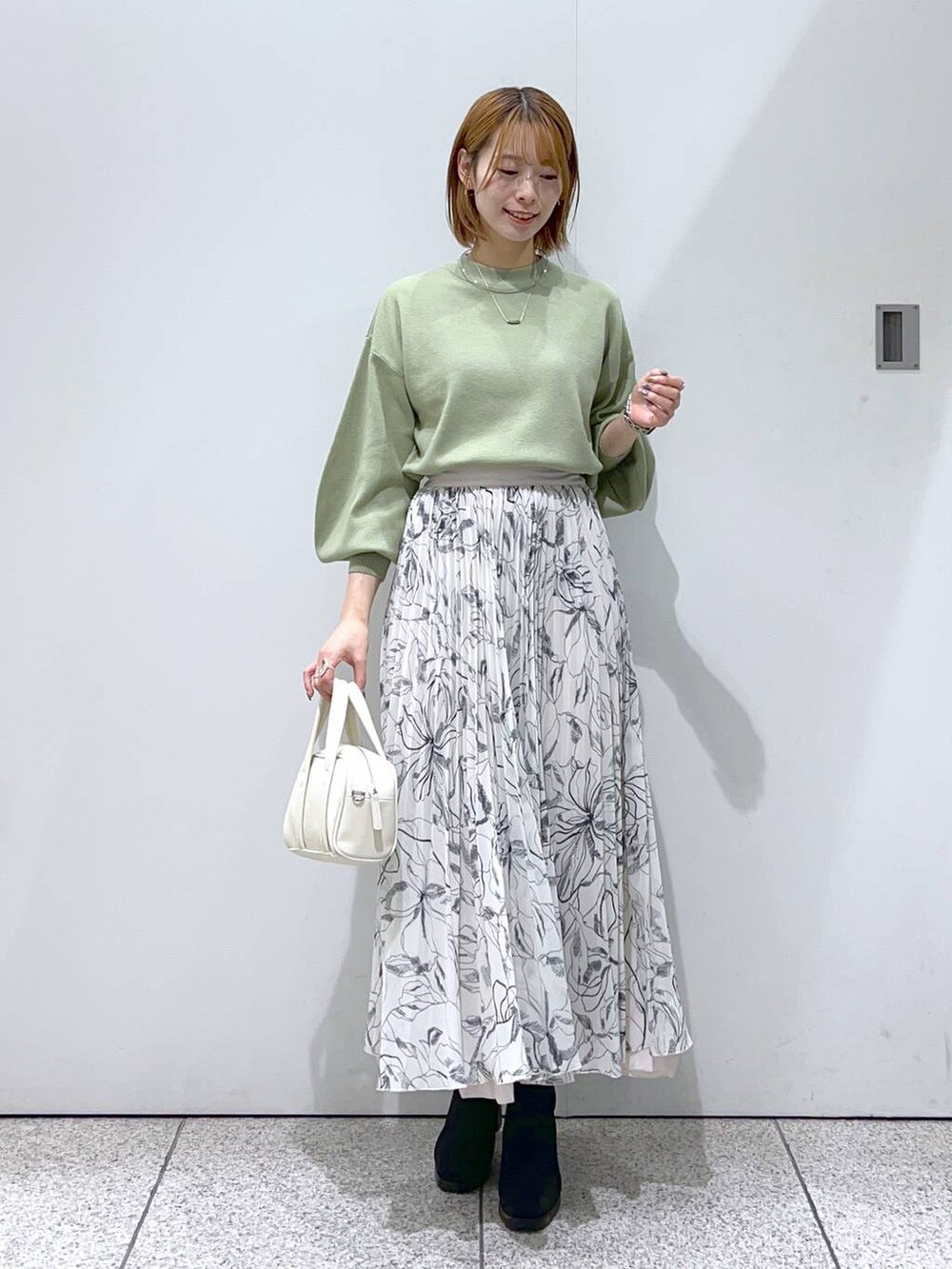 ホワイト系のブルゾン、ホワイト系のボストンバッグ、ブラック系のブーツを着用したレディースの秋コーディネートの4枚目の写真