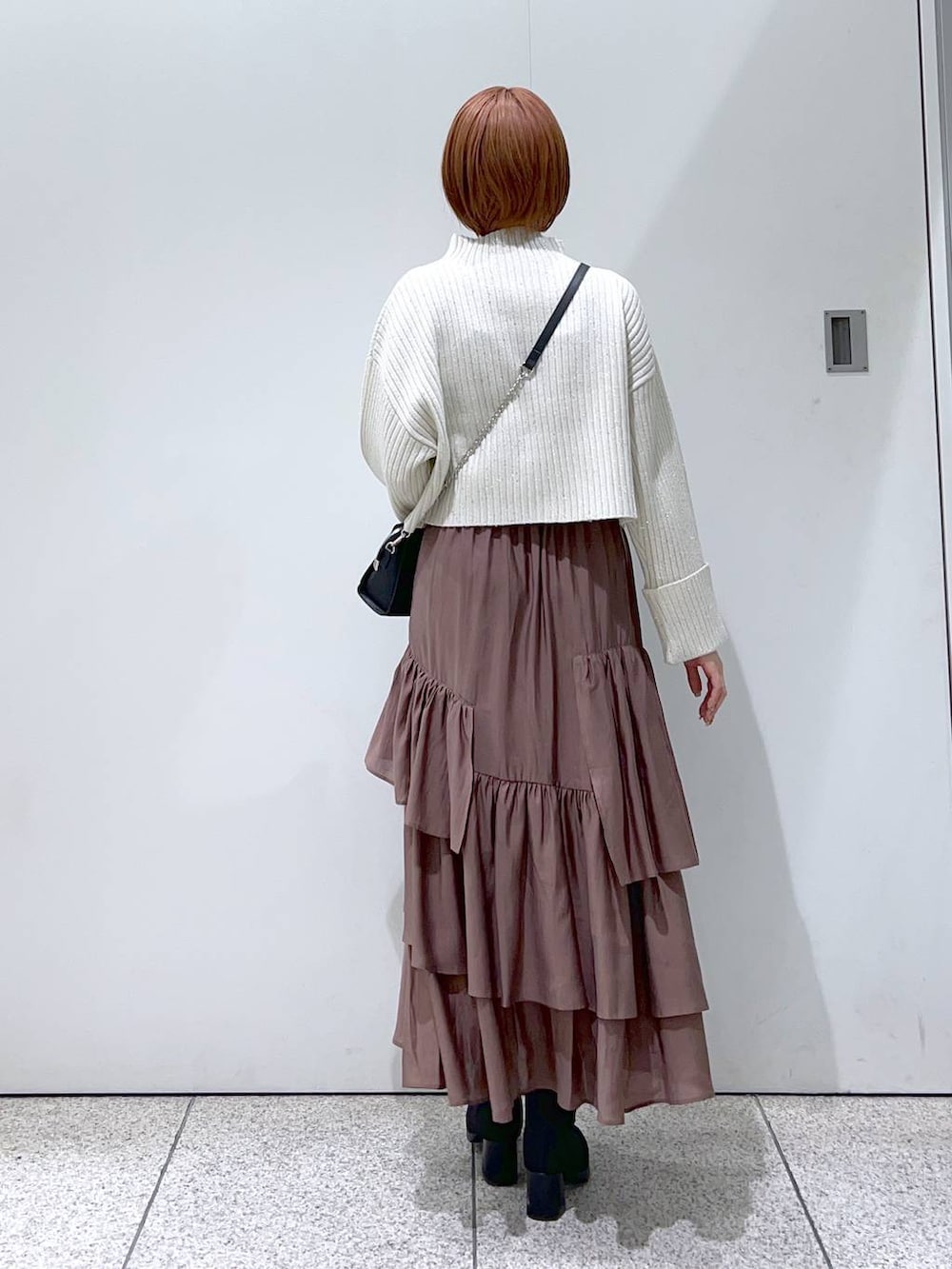 ブラック系のチェスターコート、ブラック系のボストンバッグ、ブラック系のブーツを着用したレディースの冬コーディネートの4枚目の写真