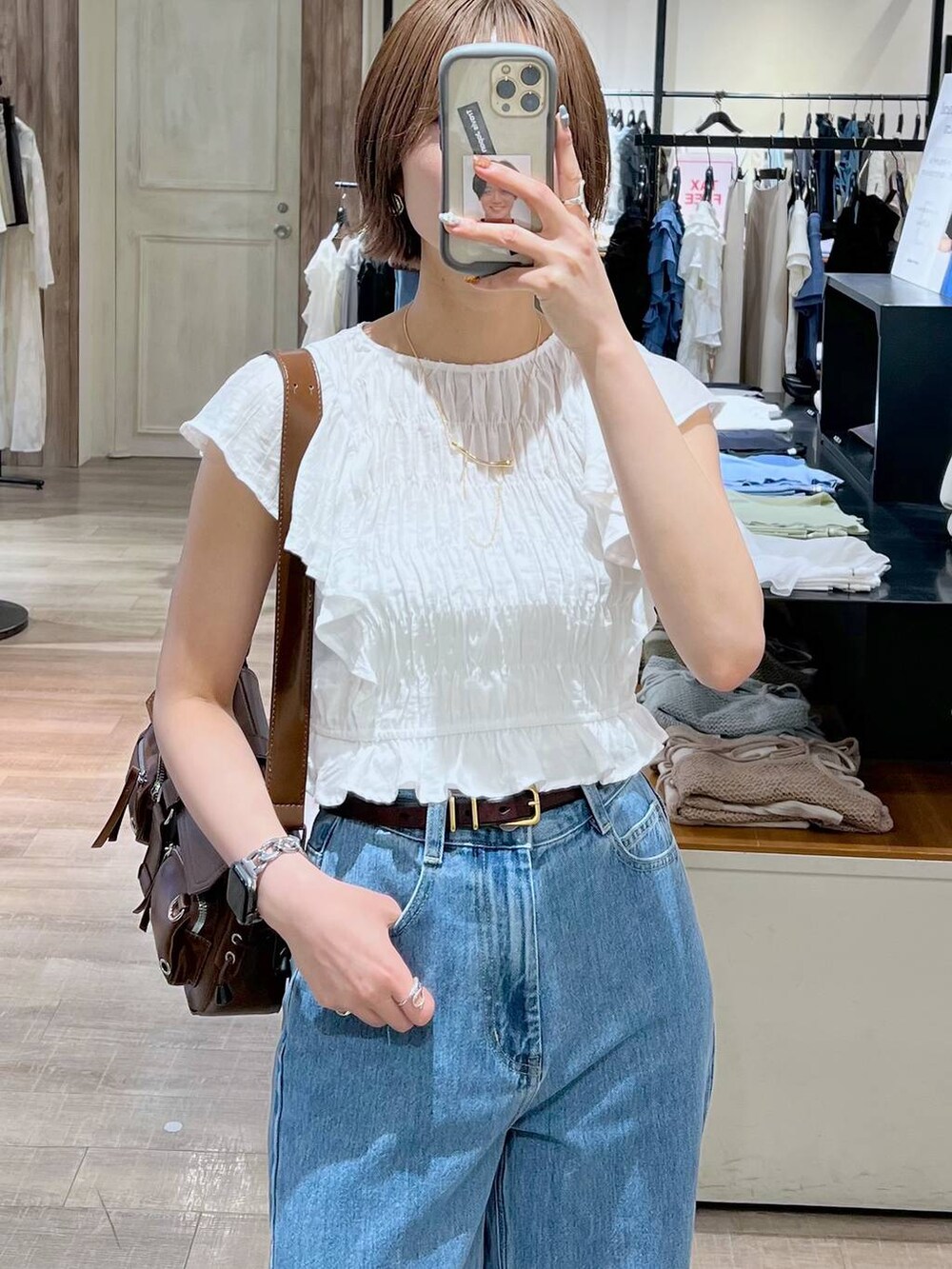 ブルー系のデニムパンツ、ホワイト系のサンダル、ブラウン系のショルダーバッグを着用したレディースの春コーディネートの5枚目の写真