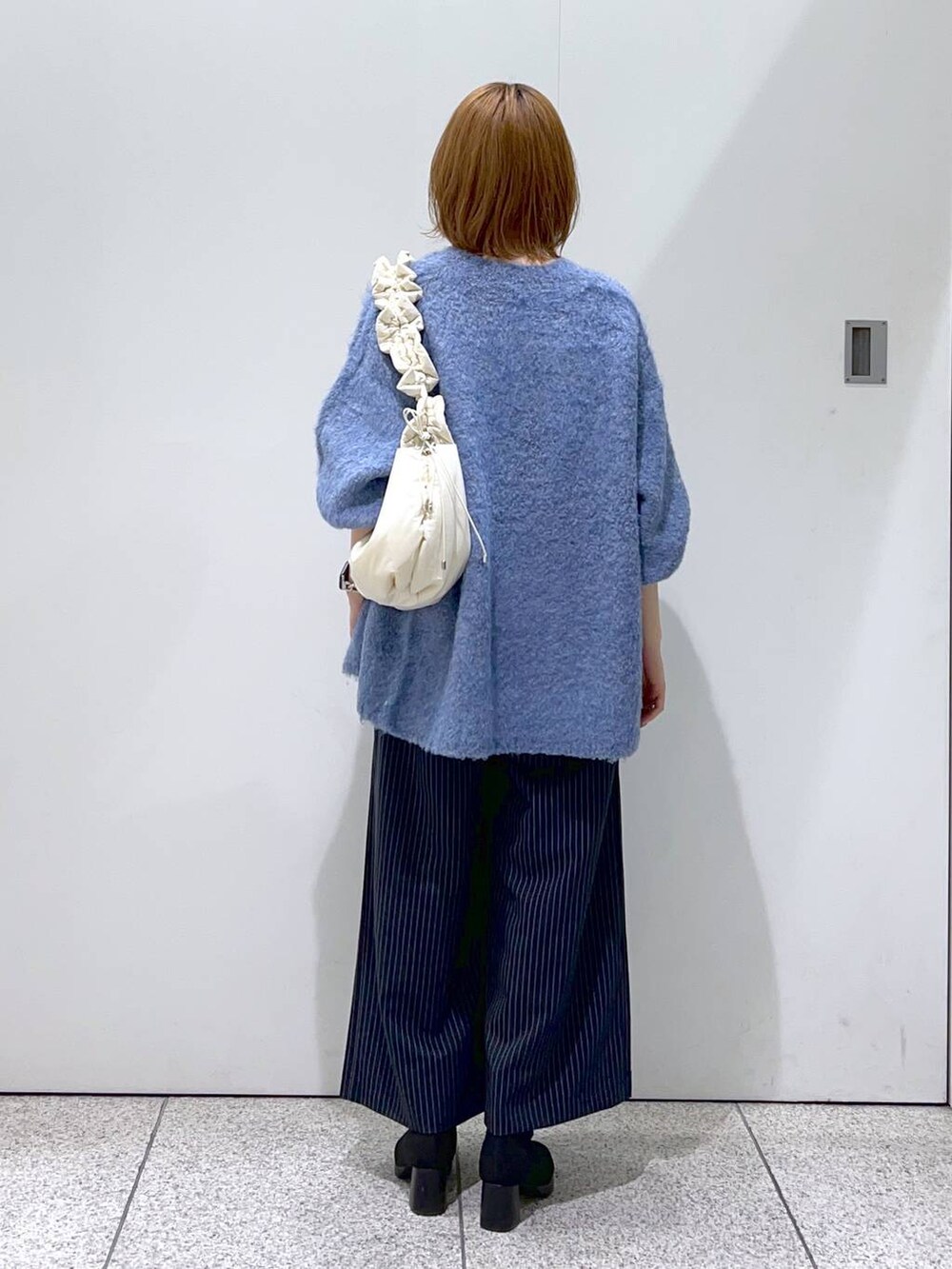 ホワイト系のタンクトップ、ホワイト系のハンドバッグ、ブラック系のブーツを着用したレディースの秋コーディネートの3枚目の写真