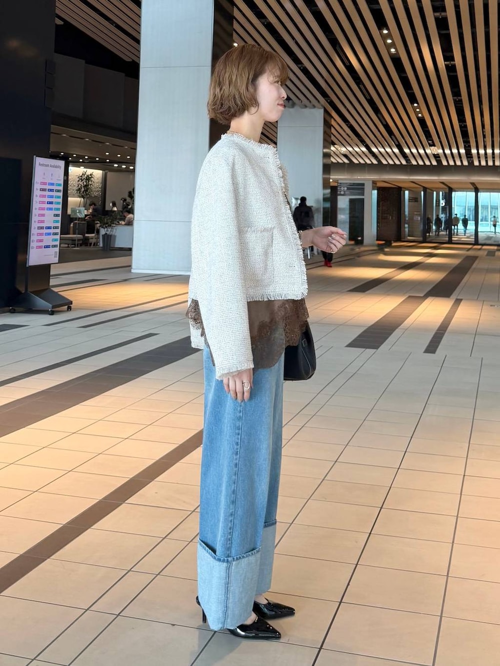 ブラック系のサンダル、ブラウン系のキャミソール、ホワイト系のノーカラージャケットを着用したレディースの春コーディネートの2枚目の写真