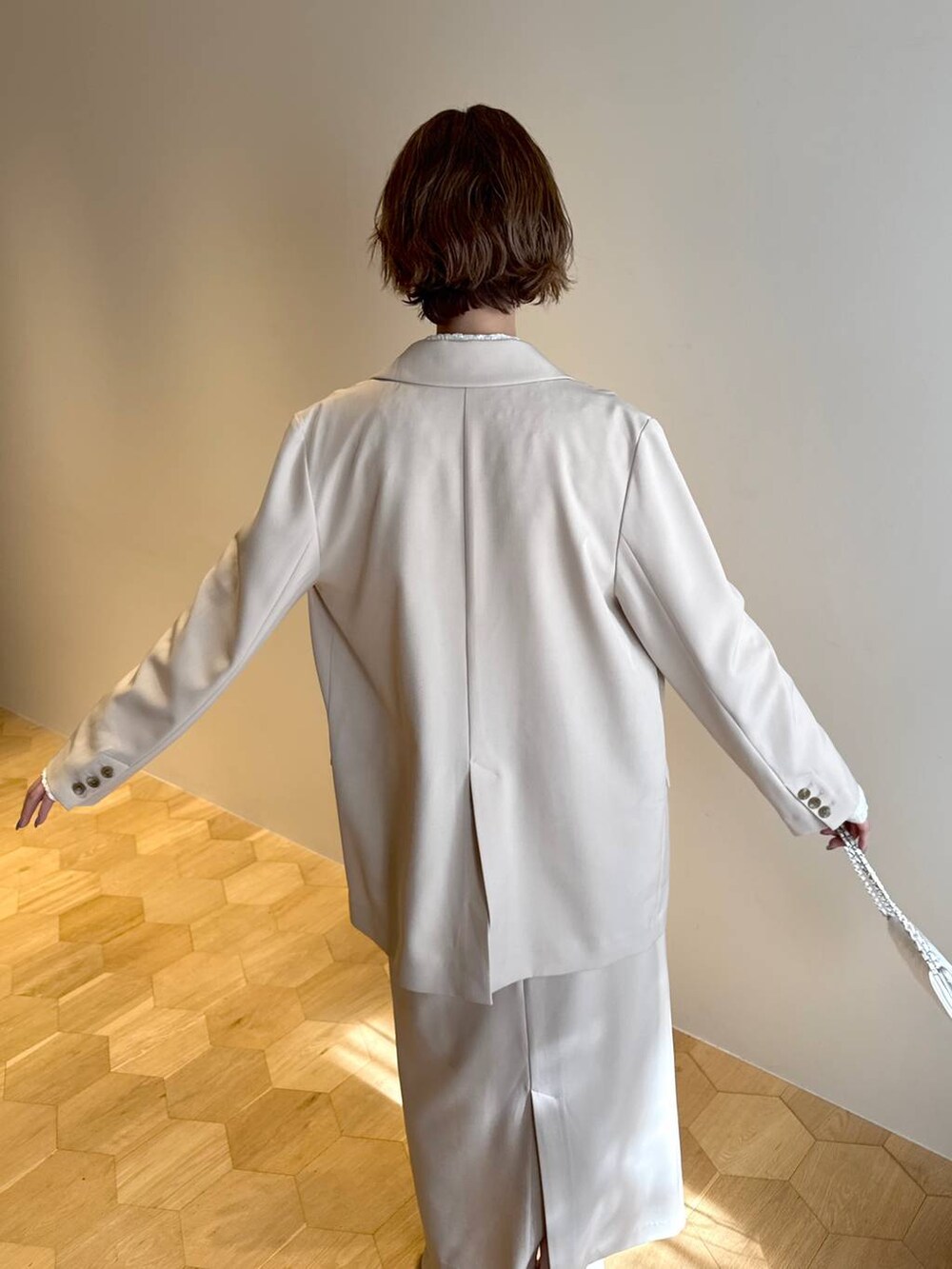 ホワイト系のサンダル、ベージュ系のテーラードジャケット、ベージュ系のスカートを着用したレディースの冬コーディネートの5枚目の写真