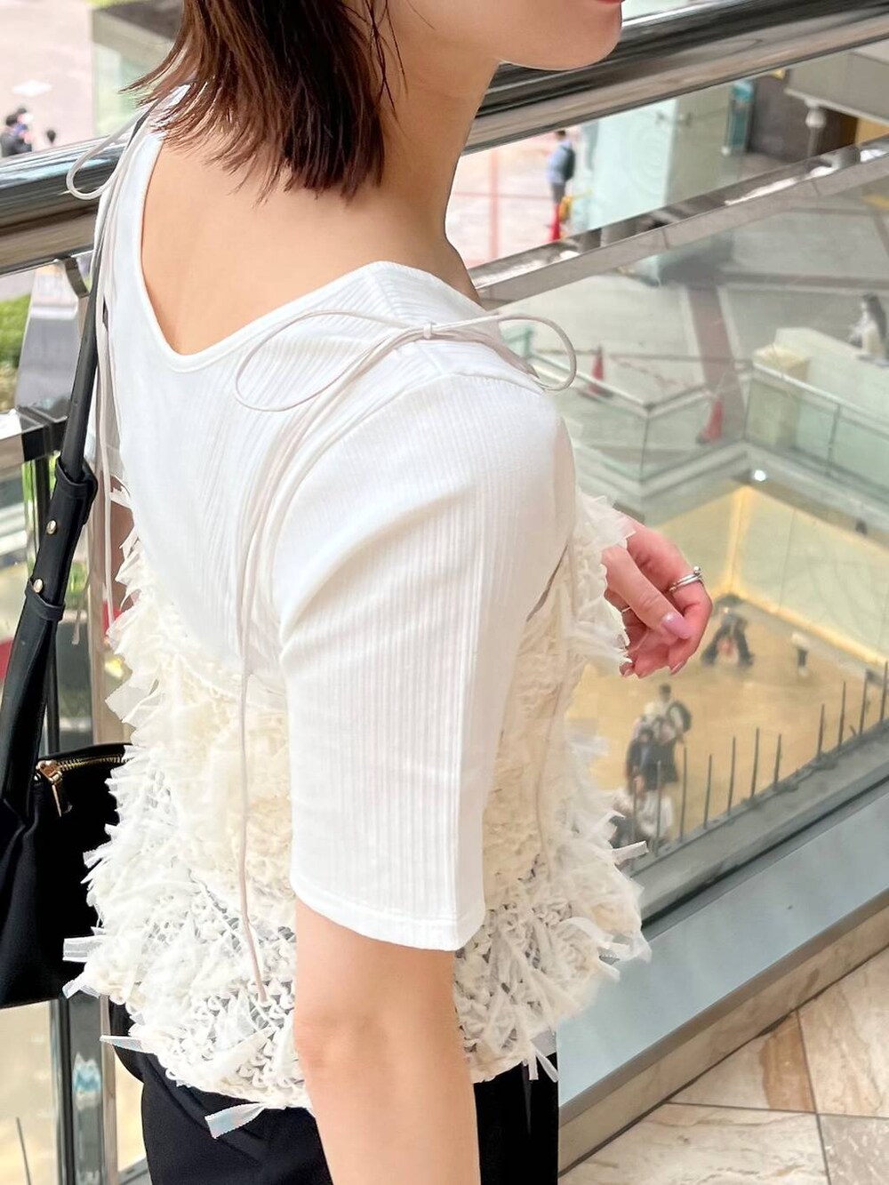 ブラック系のサンダル、ブラック系のスラックス、ブラック系のショルダーバッグを着用したレディースの春コーディネートの6枚目の写真