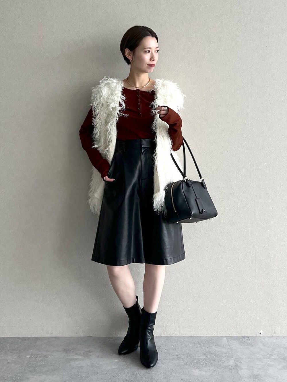 ブラック系のハンドバッグ、ホワイト系のベスト、ブラウン系のTシャツ/カットソーを着用したレディースの秋コーディネートの5枚目の写真