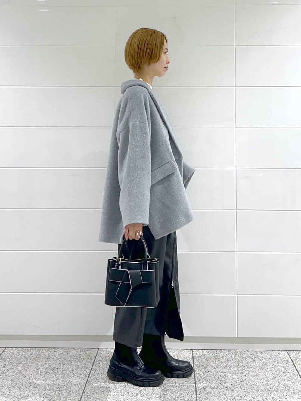 ブラック系のブーツ、ホワイト系のニット/セーター、ブラック系のショルダーバッグを着用したレディースの冬コーディネートの2枚目の写真