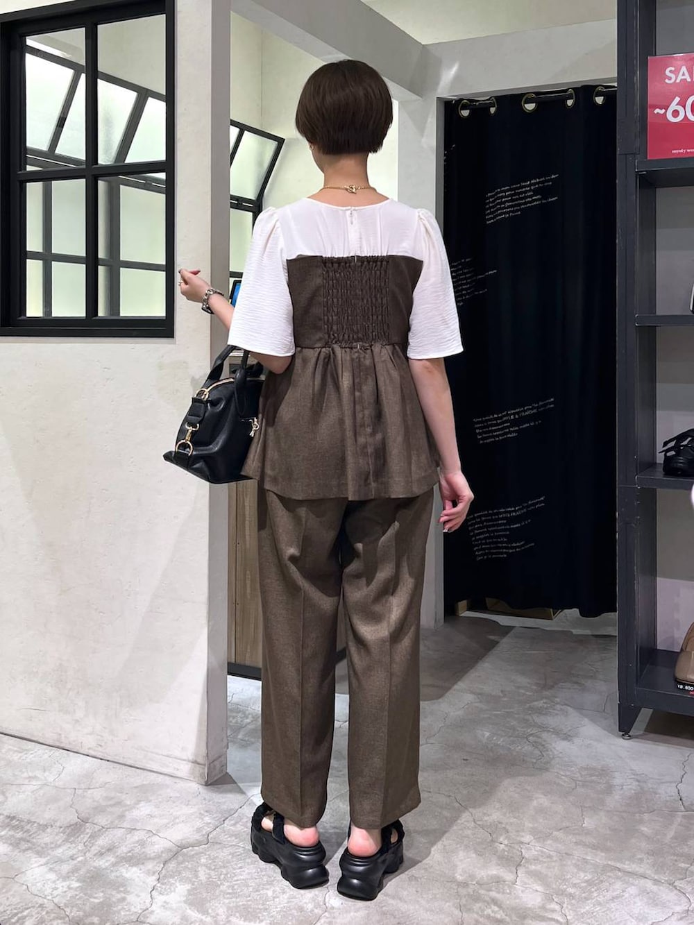 ブラック系のサンダル、ブラック系のボストンバッグ、ブラウン系のその他パンツを着用したレディースの夏コーディネートの3枚目の写真