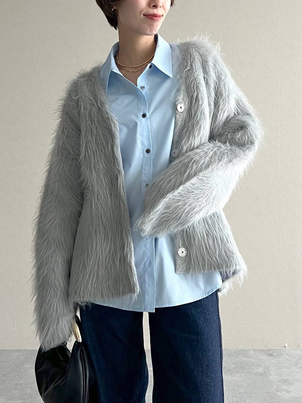 ブラック系のハンドバッグ、ブルー系のデニムパンツ、ブラック系のローファーを着用したレディースの秋コーディネートの4枚目の写真