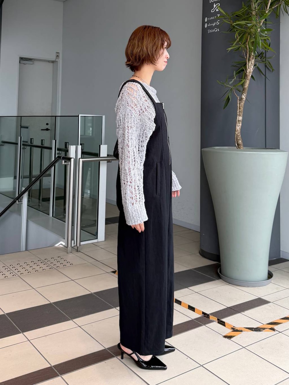 グレー系のニット/セーター、ブラック系のサンダル、ブラック系のショルダーバッグを着用したレディースの春コーディネートの2枚目の写真