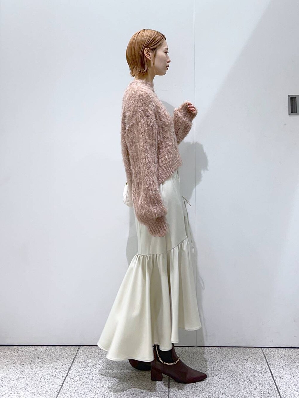 ホワイト系のショルダーバッグ、ブラウン系のブーツ、ブラウン系のニット/セーターを着用したレディースの冬コーディネートの2枚目の写真