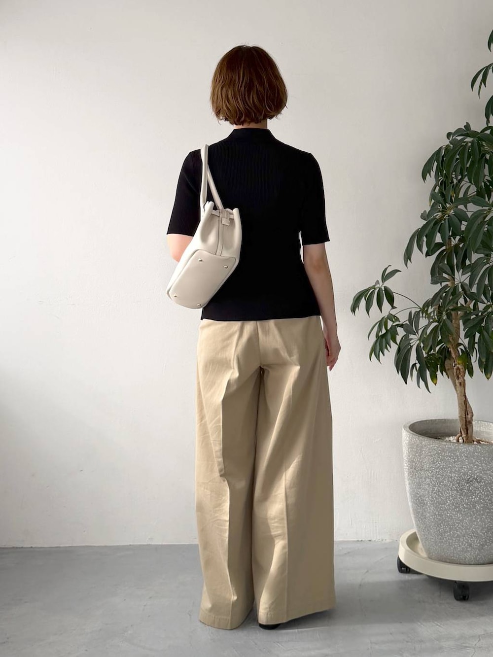 ブラック系のカーディガン/ボレロ、ベージュ系のチノパンツ、ホワイト系のショルダーバッグを着用したレディースの春コーディネートの3枚目の写真