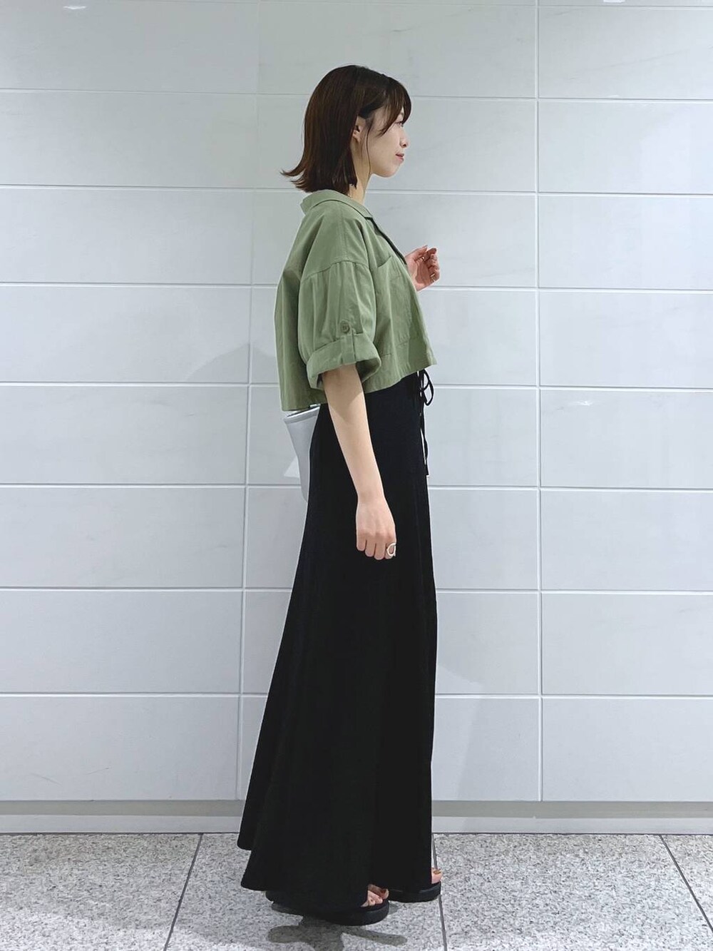 ブラック系のサンダル、シルバー系のハンドバッグ、グリーン系のミリタリージャケットを着用したレディースの夏コーディネートの3枚目の写真