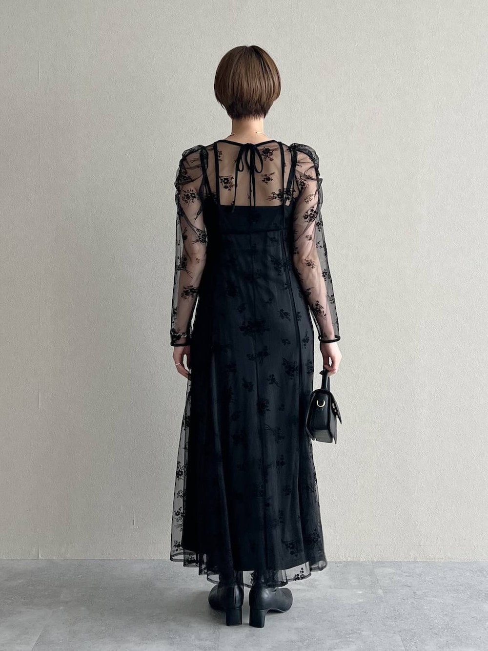 ブラック系のワンピース、パープル系のチェスターコート、ブラック系のブーツを着用したレディースの秋コーディネートの6枚目の写真