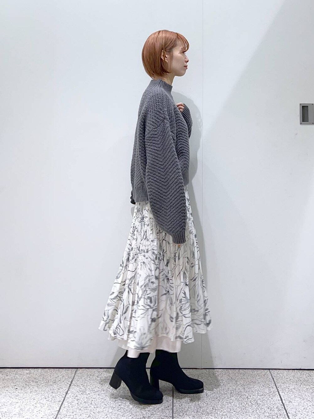 ブラック系のブーツ、ホワイト系のスカート、ブラック系のトートバッグを着用したレディースの冬コーディネートの2枚目の写真