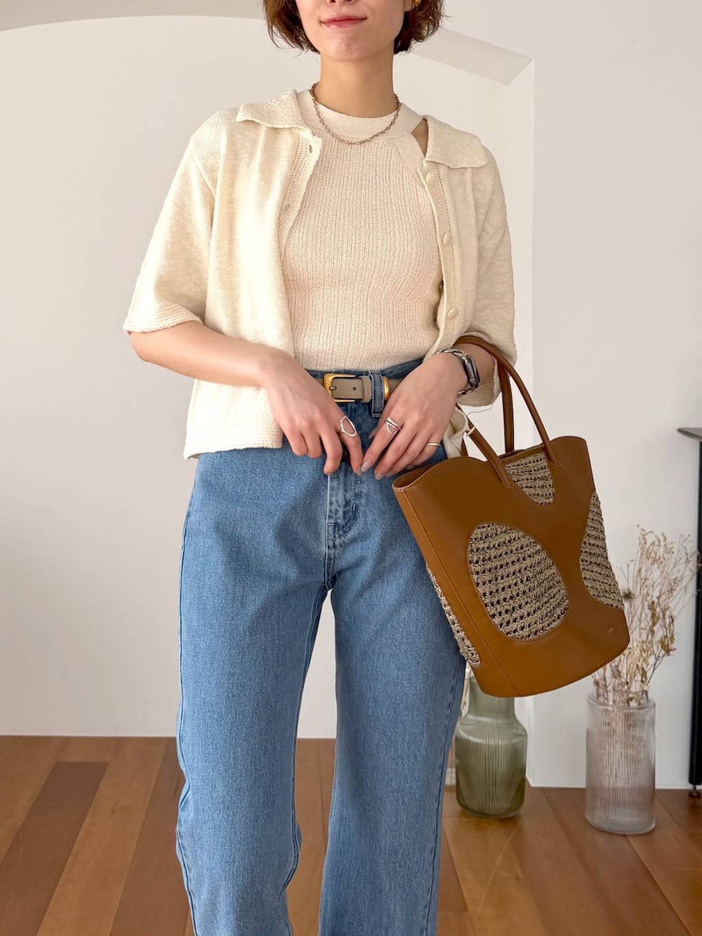 ブラウン系のトートバッグ、ブルー系のデニムパンツ、ブラック系のサンダルを着用したレディースの春コーディネートの4枚目の写真