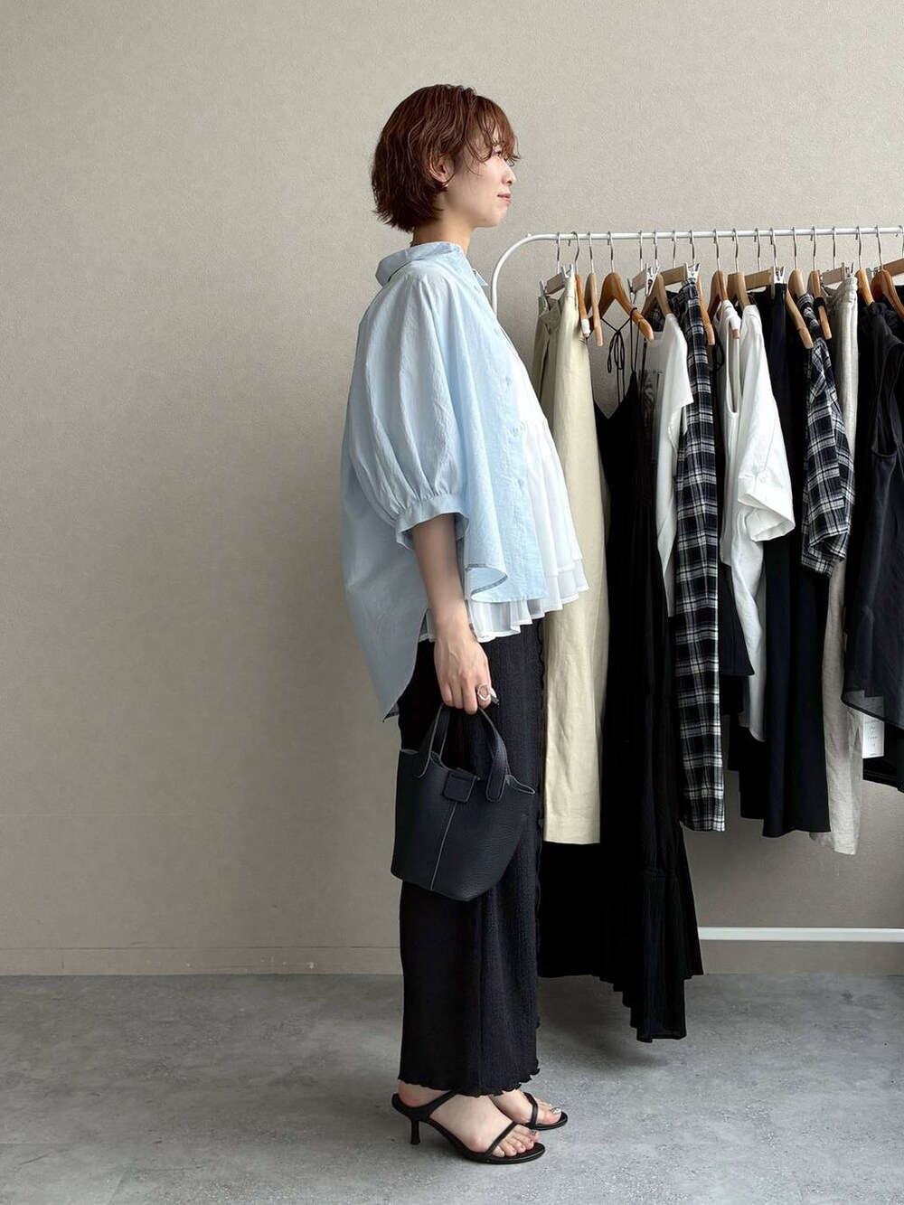 ブラック系のスカート、グレー系のニット/セーター、ブルー系のシャツ/ブラウスを着用したレディースの夏コーディネートの2枚目の写真